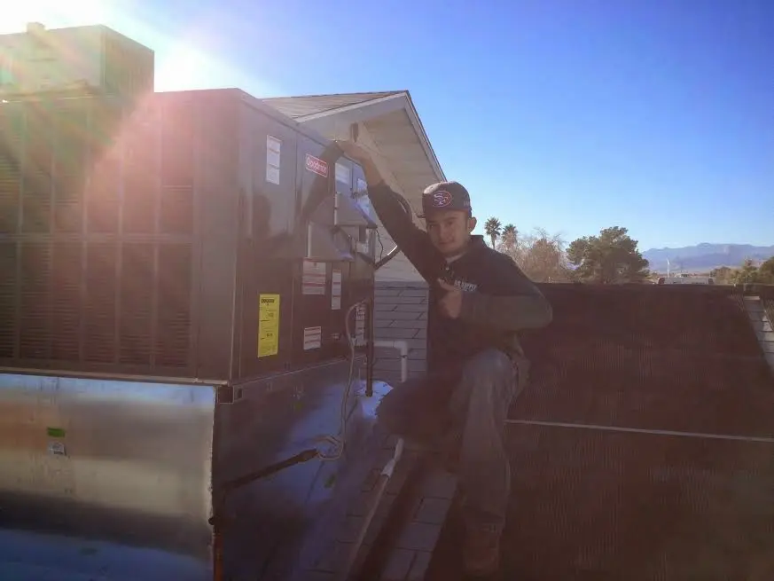 HVAC technician performing AC Tune-Up on a rooftop unit in Lysander